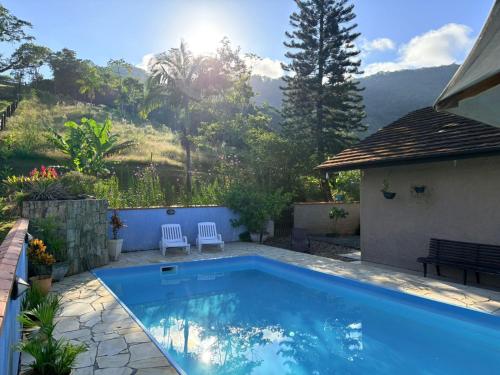 a swimming pool with two chairs next to a house at Paraíso Pomerode in Pomerode