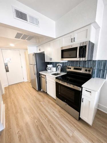 a kitchen with white cabinets and a stove top oven at Boardwalk Noir - Oceanfront Studio Yachtsman 404 in Myrtle Beach