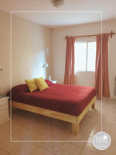 a bedroom with a bed with a red blanket and a window at SAN TAURO VIEDMA in Viedma