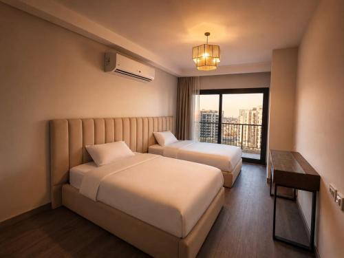 a hotel room with two beds and a window at ZED Towers City View Apartment in Sheikh Zayed