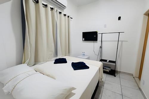 two white beds in a room with a television at Abaíra Serra Azul Suítes 02 - Centro in Petrolina