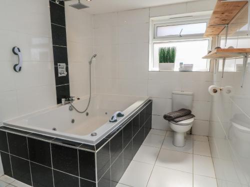a white bathroom with a tub and a toilet at Bayview Cottage in Bournemouth