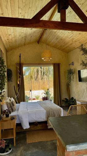 a bedroom with a bed and a large window at EcoRefúgio Verde - iUna in Ibiúna