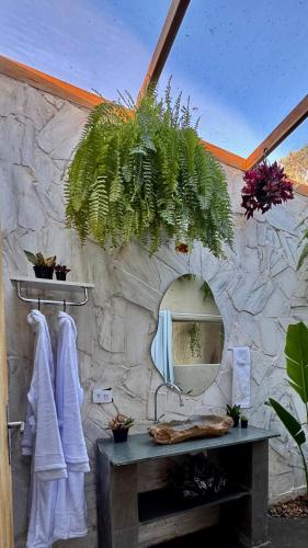 a bathroom with a stone wall with a mirror at EcoRefúgio Verde - iUna in Ibiúna