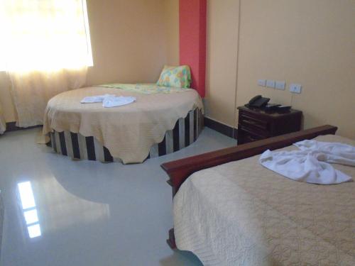a hotel room with two beds and a dresser at Hotel Platinum Class in Nueva Loja
