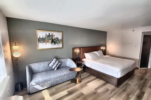 a hotel room with a bed and a couch at Radisson Hotel Detroit Metro Airport in Romulus