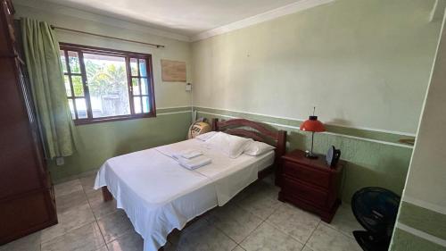 a bedroom with a bed with white sheets and a window at Casa com Piscina Privativa e Churrasqueira in Araruama