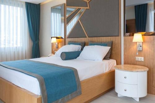 a bedroom with a large bed with blue curtains at Graf Victor Hotel - All Inclusive Non Alcoholic Drinks in Çamyolu