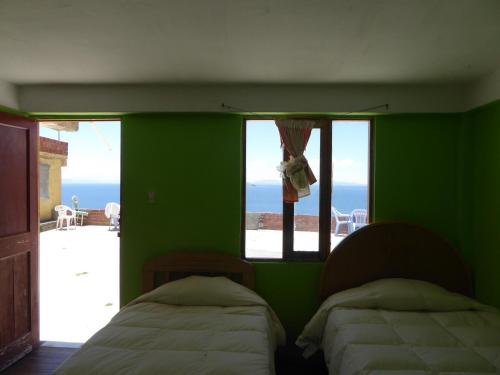 a green room with two beds and a window at Ecolodge Amanecer in Comunidad Yumani