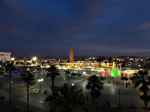 a city at night with a clock tower and palm trees at Luxury Apartment Elevator FIBER WIFI in Oujda