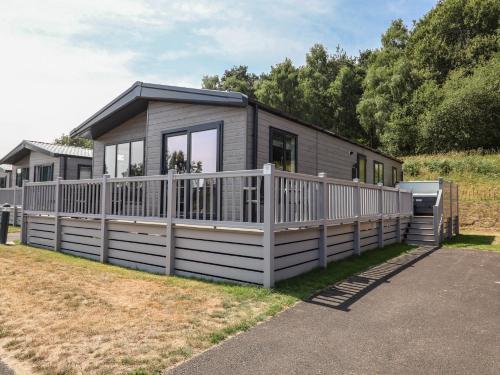 a small house with a white fence in a yard at Cedar Lodge 2 Bedrooms with hot tub in Northwich