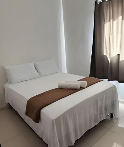 a white bed with two towels on top of it at Abaíra Serra Azul Loft 5 - Orla - Centro in Petrolina