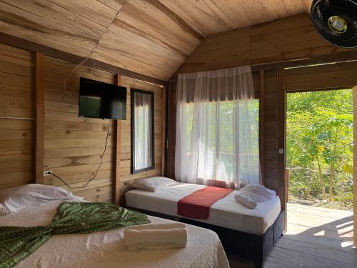 two beds in a wooden room with a window at Cabaña y restaurante vikana in Nuquí