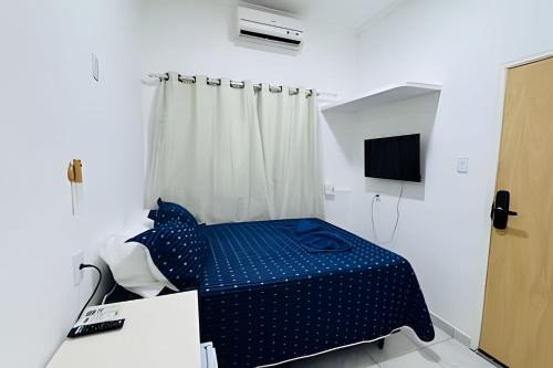 a bedroom with a blue bed and a television at Abaíra Serra Azul Suítes 04 - Centro in Petrolina