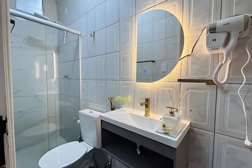 a white bathroom with a toilet and a sink at Abaíra Serra Azul Suítes 04 - Centro in Petrolina