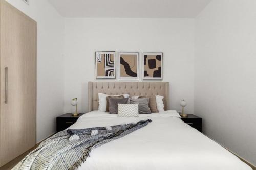 a bedroom with a large white bed with two tables at Waterfront Yas 1BR near F1 & Ticket Savings in Abu Dhabi