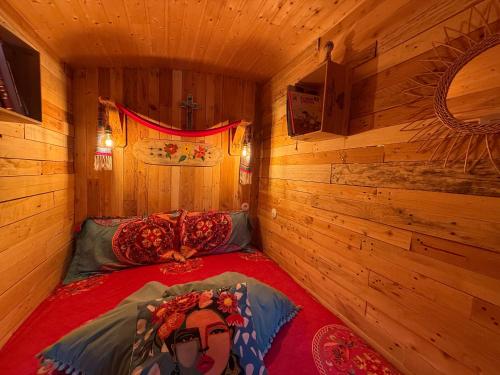 a room with a bed in a wooden cabin at Roulotte de Charme in Bréconchaux