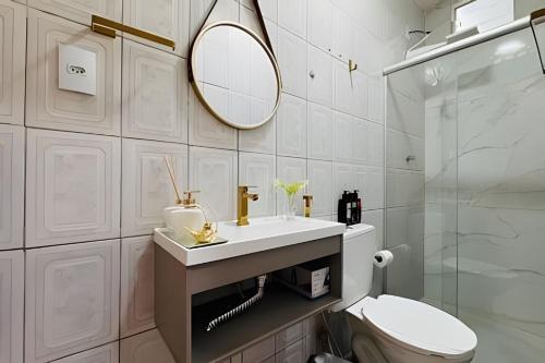 a bathroom with a sink and a toilet and a mirror at Abaíra Serra Azul Suítes 03 - Centro in Petrolina