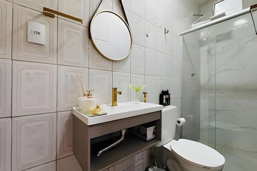 a bathroom with a sink and a toilet and a mirror at Abaíra Serra Azul Suítes 01 - Centro in Petrolina