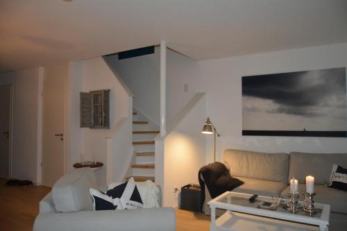 ein Wohnzimmer mit einem Sofa und einer Treppe in der Unterkunft Ferienhaus MeeresRauschen in Olpenitz
