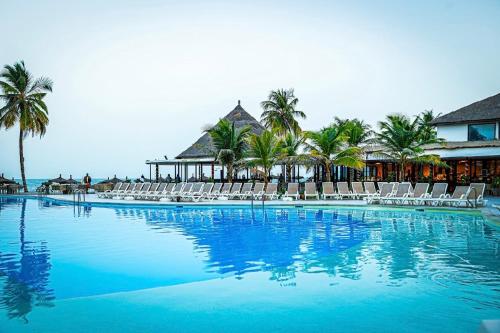 a large swimming pool with chairs and the ocean at m hadji premium in Dakar