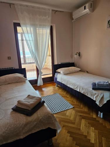 two beds in a room with a window and a rug at Holiday Sparks in Jadranovo