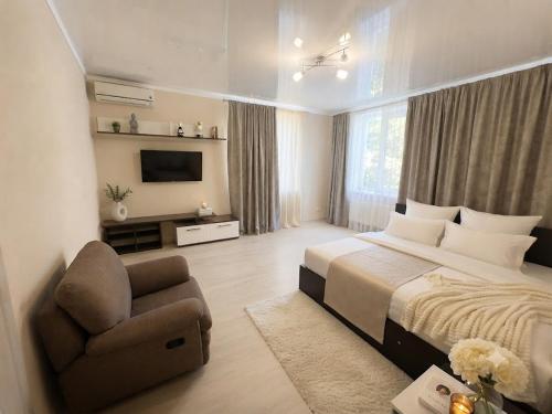 a bedroom with a bed and a chair and a television at Vila LOLO in Chişinău