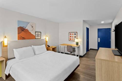 a bedroom with a white bed and a desk with a laptop at Spark By Hilton Prestonsburg in Prestonsburg