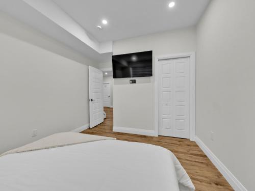 a white bedroom with a bed and a tv at Windsor Perfect Stay in Windsor
