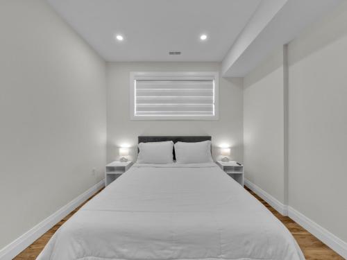 a white bed in a white room with two lamps at Windsor Perfect Stay in Windsor