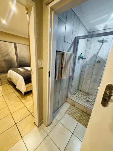 a bathroom with a walk in shower next to a bed at Hei Stays One Bed Apartment in Bronkhorstspruit