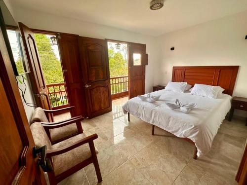 ein Schlafzimmer mit Bett, Stuhl und Fenstern in der Unterkunft Los Barranqueros Hotel in Salento