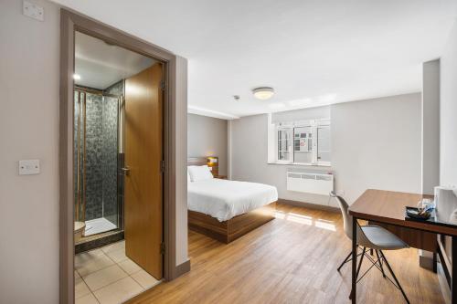 a bedroom with a bed and a desk and a table at The Mitre Hotel Brighton in Brighton & Hove