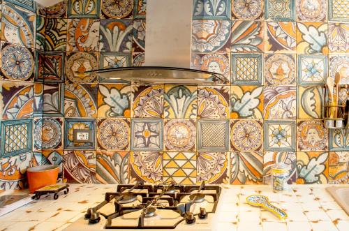 a kitchen with a tile wall with a stove at Chibedda Dimora Lia in Acitrezza