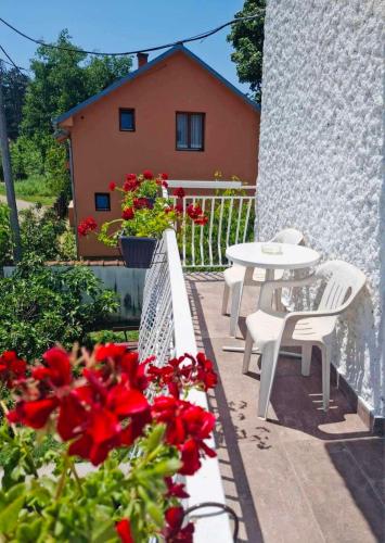 a patio with a table and chairs and red flowers at Privatni smeštaj Nanica in Mataruška Banja