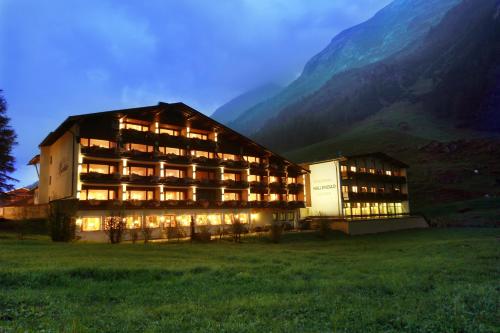 a large building in a field with a mountain at Thermal-Badhotel Kirchler in Tux