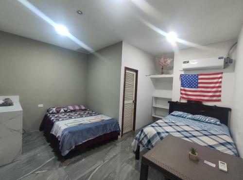 a room with two beds and an american flag on the wall at Hospedaje Blue House - Consulado americano - Habitacion 2 in Guayaquil