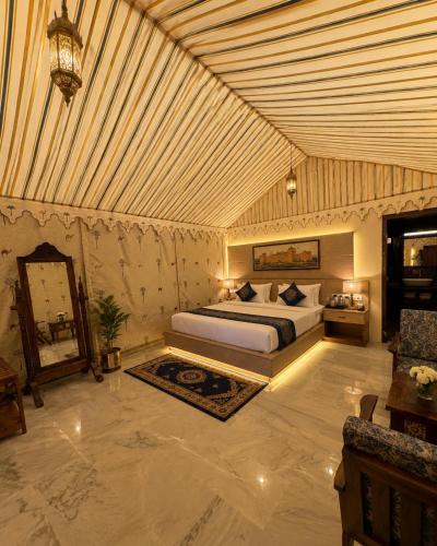 a bedroom with a bed and a mirror in it at Mahindra Desert Resort & Camp in Jaisalmer