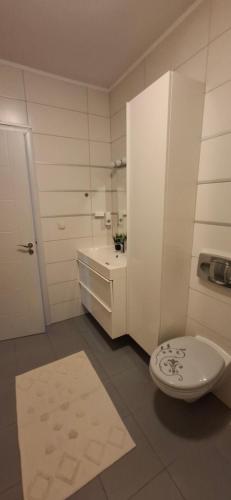 a white bathroom with a toilet and a sink at LaLuna House in Cernik