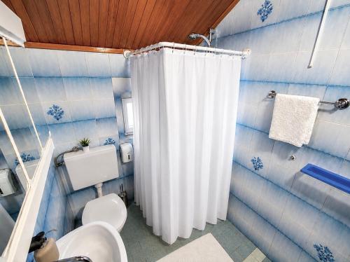 a bathroom with a white shower curtain and a toilet at Guest House Kovačević in Korenica