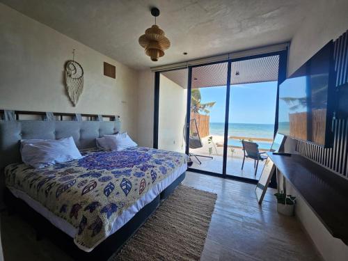 a bedroom with a bed and a view of the ocean at Beachfront , alberca y terraza in Telchac Puerto