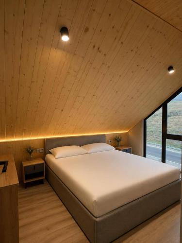 a bedroom with a large bed and a large window at Highland Hils in Garni