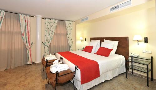 a hotel room with a large bed with red pillows at Hotel Salobreña Suites in Salobreña