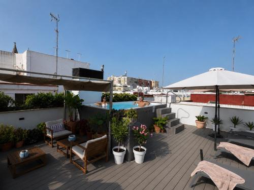 a patio with furniture and an umbrella on a roof at Aparthotel Luz de Gades - Suites Spa Gym - Adults Only in Cádiz