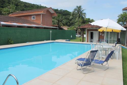 a swimming pool with two chairs and an umbrella at Pousada Porto Paraiso, o seu Paraíso Escondido no Guarujá in Guarujá