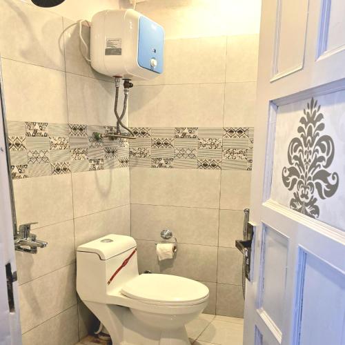 a bathroom with a toilet and a paper dispenser on the wall at Bhurban Nights - Glass Bed Murree Hills View - Lift - 15 Minutes from Murree & Mallroad in Murree
