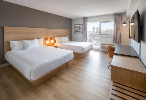 a hotel room with two beds and a desk at Norwood Hotel in Winnipeg