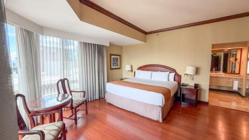 a hotel room with a bed and a table and chairs at Clarion Suites Guatemala City in Guatemala