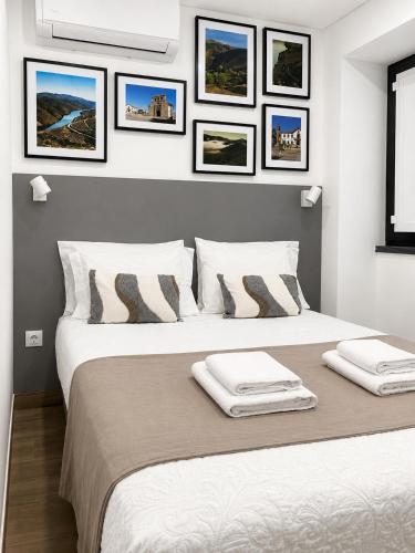 a bedroom with two beds with pictures on the wall at Casas da Barca in Vila Nova de Foz Coa
