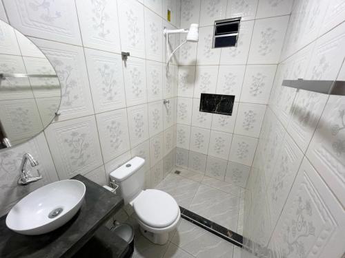 a bathroom with a toilet and a sink and a mirror at Aura Mar Flat in Baía Formosa
